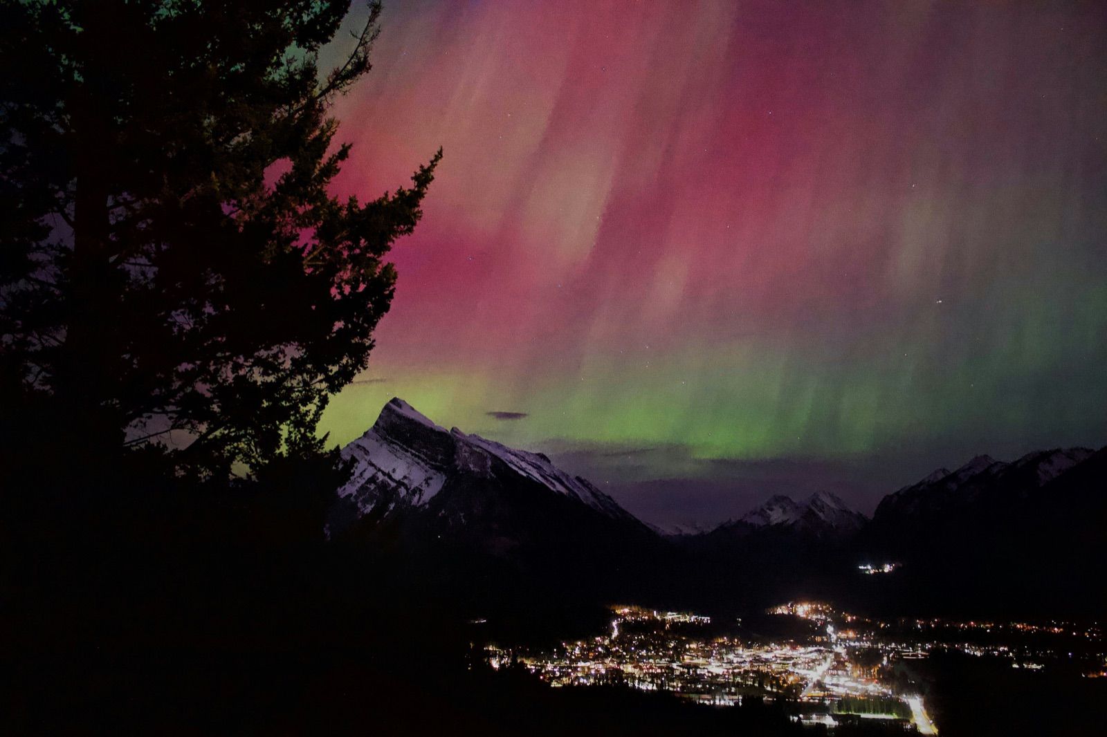 Orange and purple aurora over Banff town and Mount Rundle — Banff Journey stargazing tour