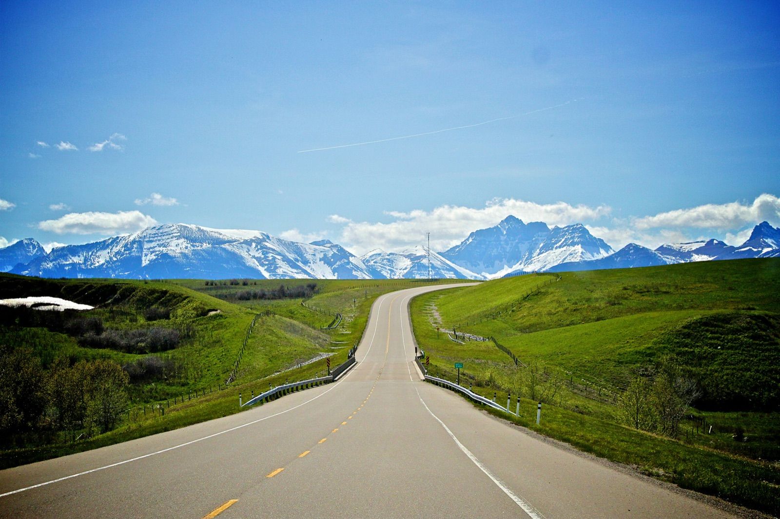 Road into Waterton Lakes National Park beneath snowy peaks — Banff Journey Waterton Lakes tour